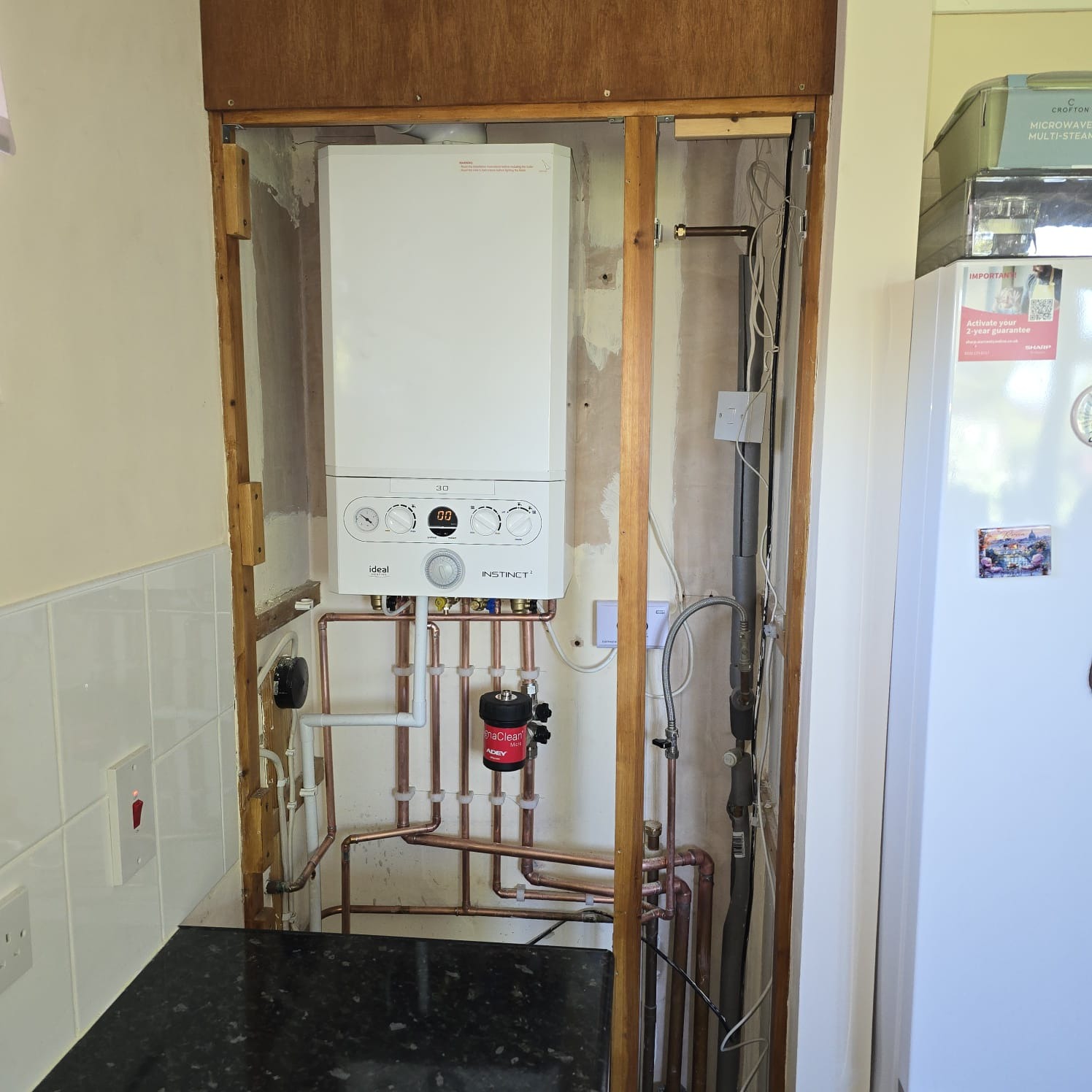 Ideal Instinct combi boiler recessed into a wooden kitchen cabinet after installation