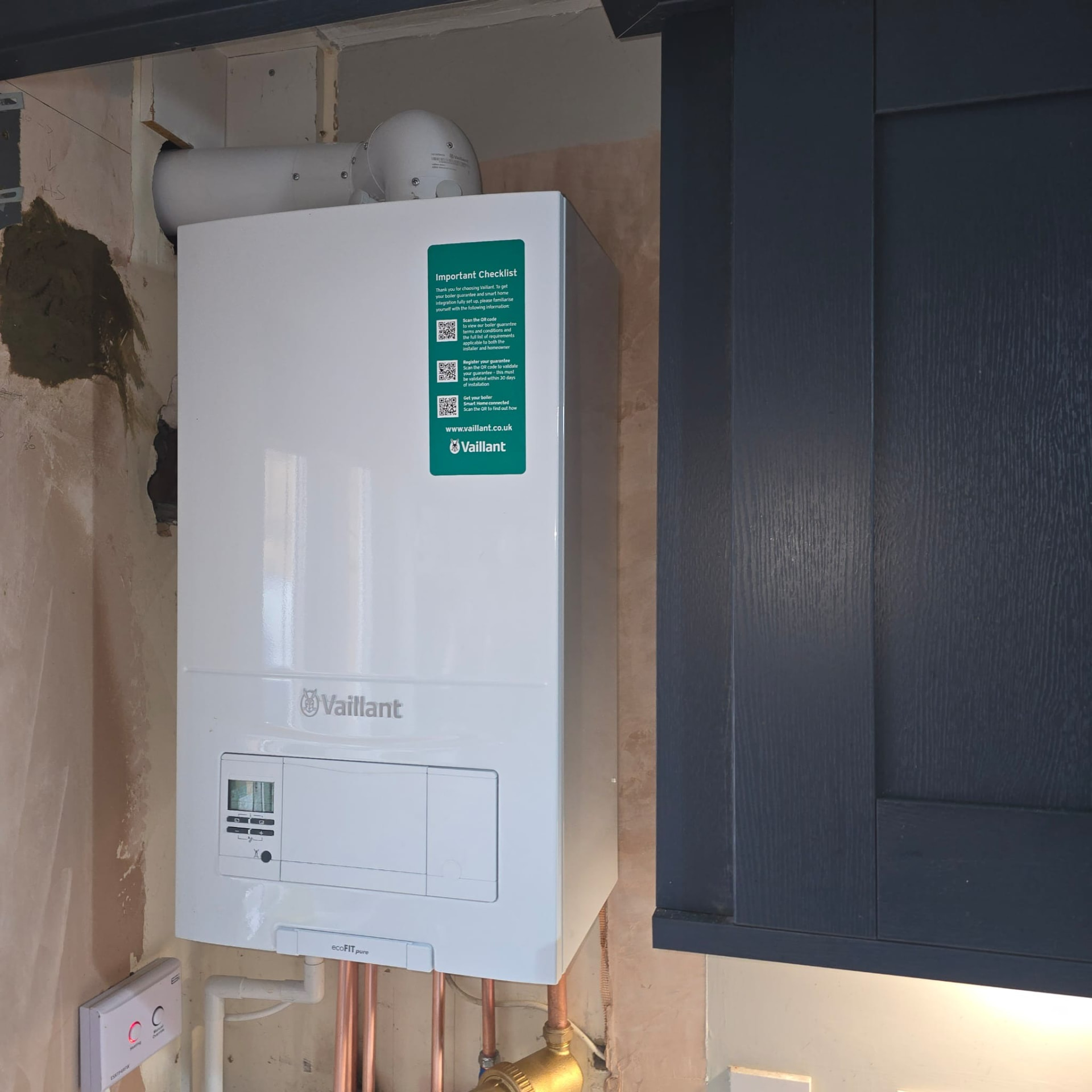 Vaillant combi boiler fitted beside dark blue kitchen units in an Essex property