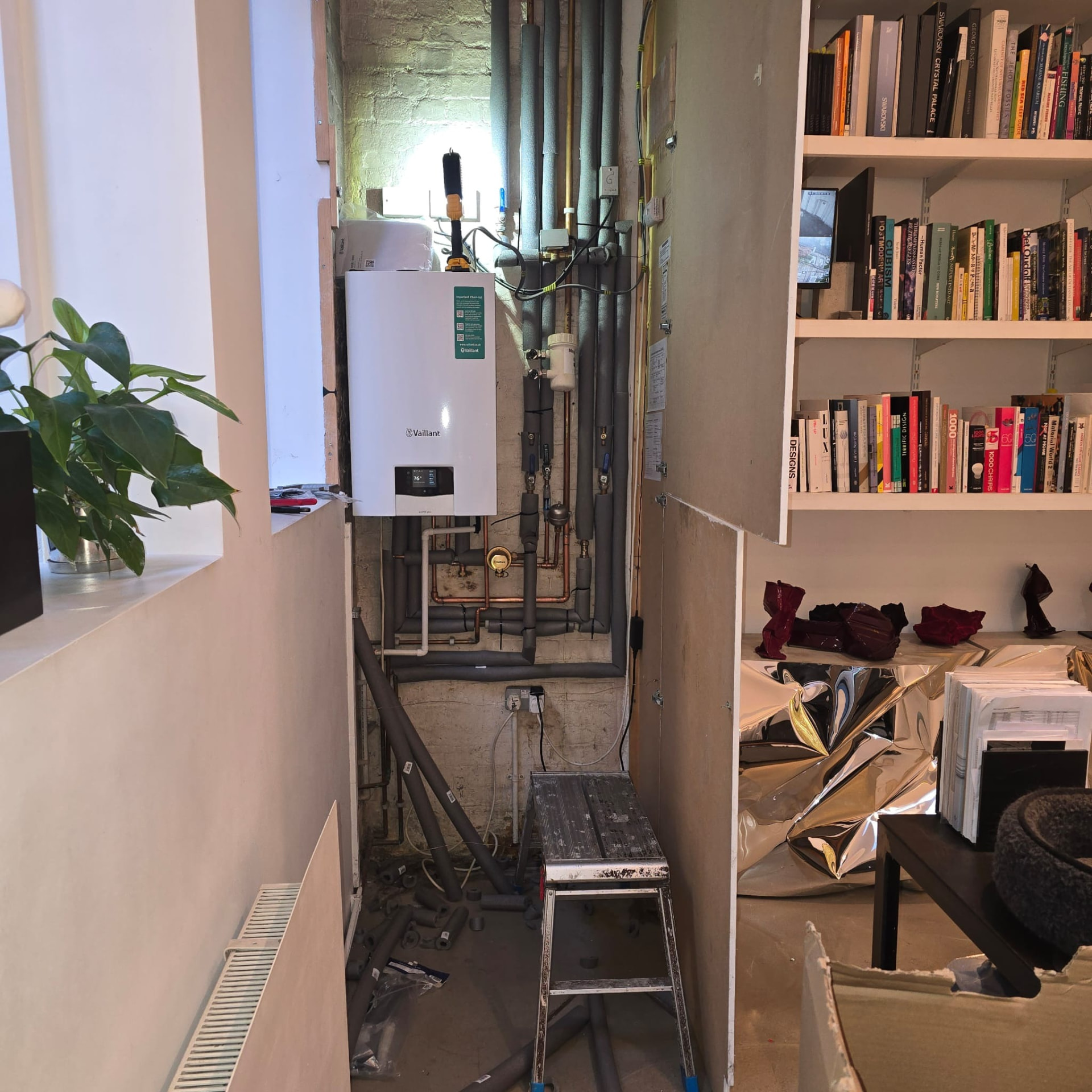 Boiler installation in progress with insulated pipework and access equipment on site
