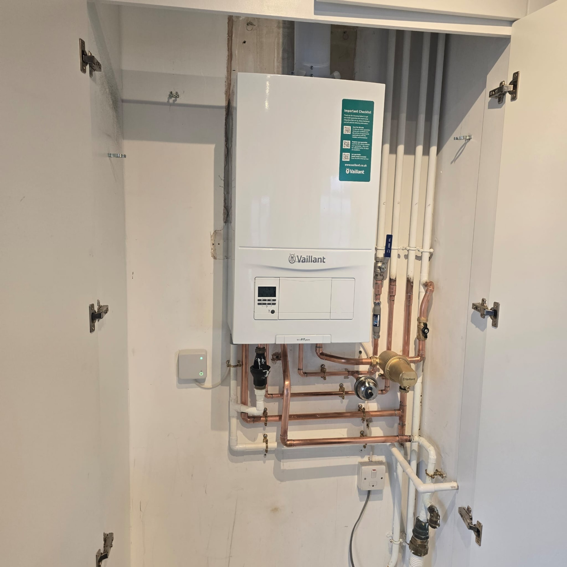 Boiler installation inside a large cupboard with copper fittings and insulated pipe runs