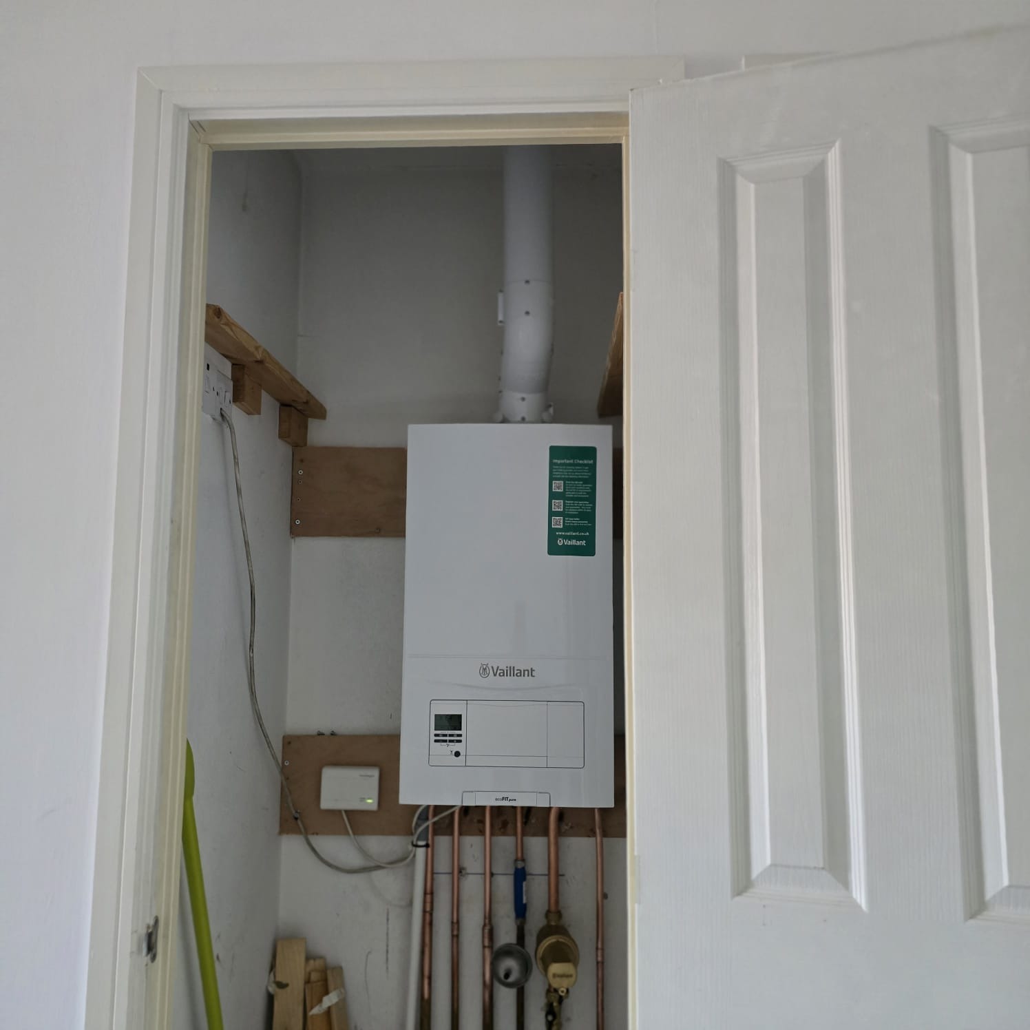 Vaillant boiler installed in a white airing cupboard with shelving retained