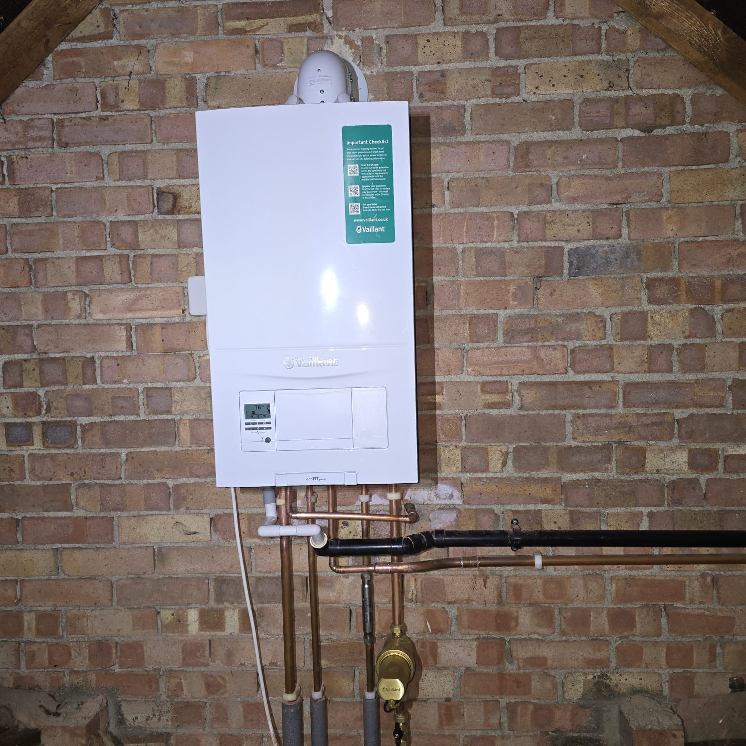 Vaillant combi boiler installed on a brick loft wall with insulated pipework by FHP Heating
