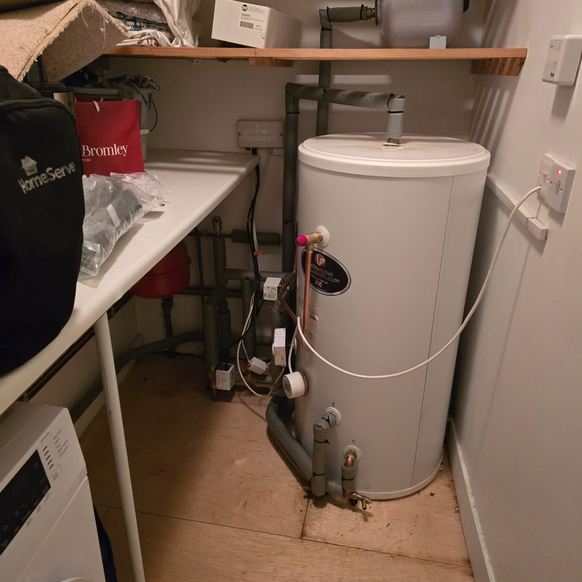 Hot water cylinder installed in a storage room with tidy pipe runs