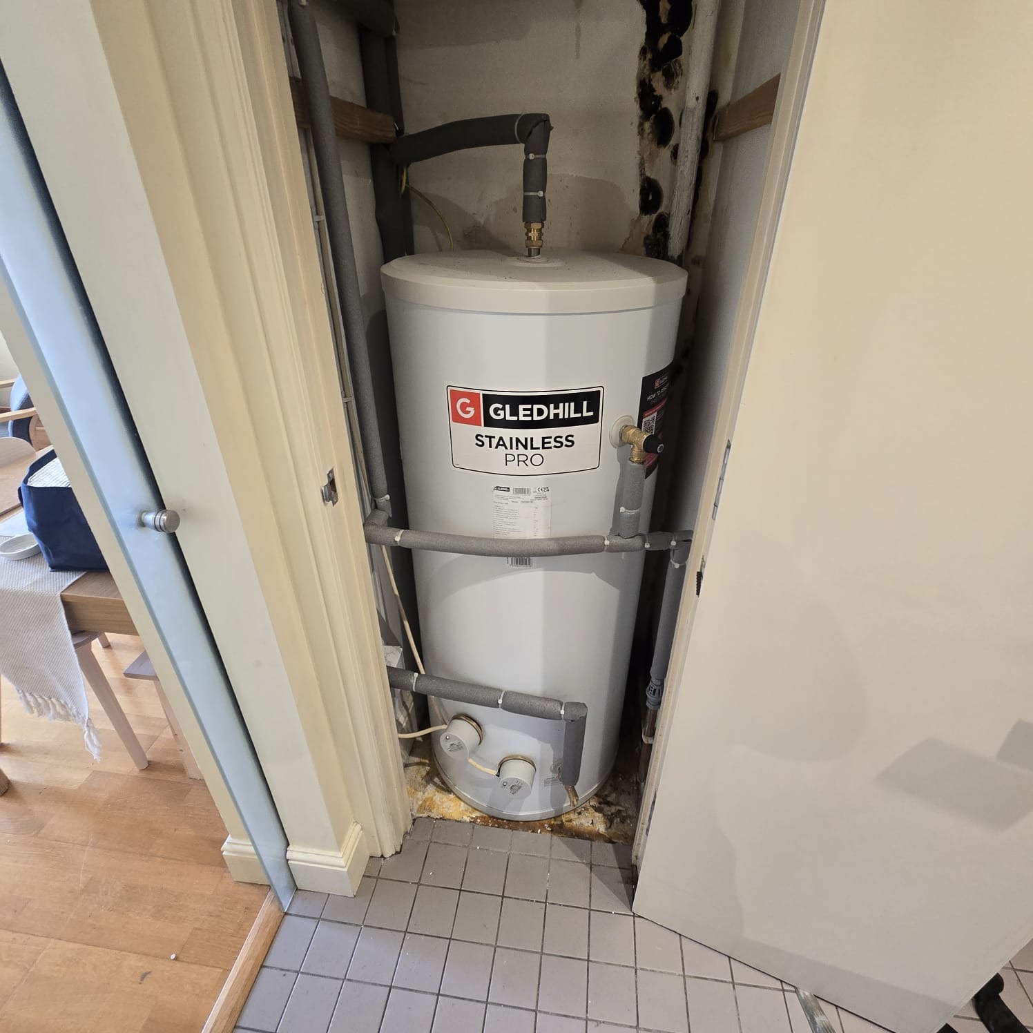 Gledhill hot water cylinder installation in a white cupboard with valves and controls