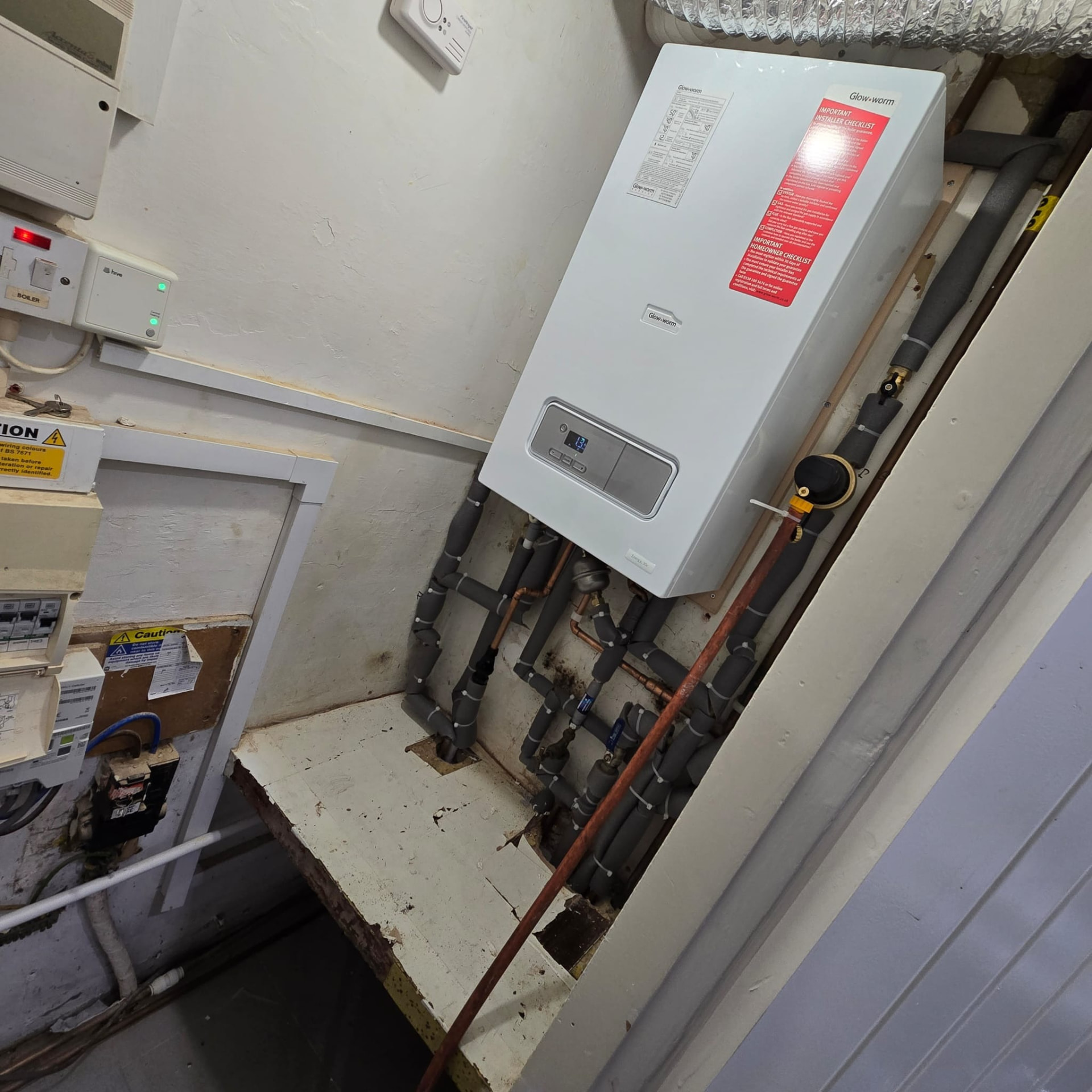 Glow-worm boiler in a utility room with grey insulated heating pipework
