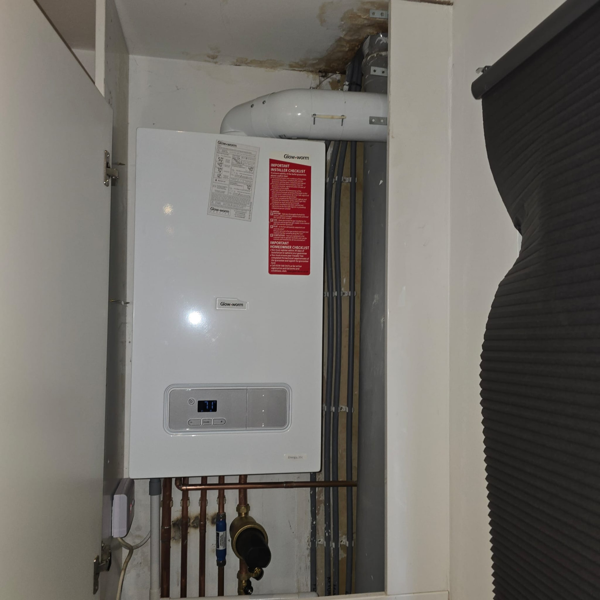 Glow-worm boiler flue connection and vertical pipework inside a cupboard
