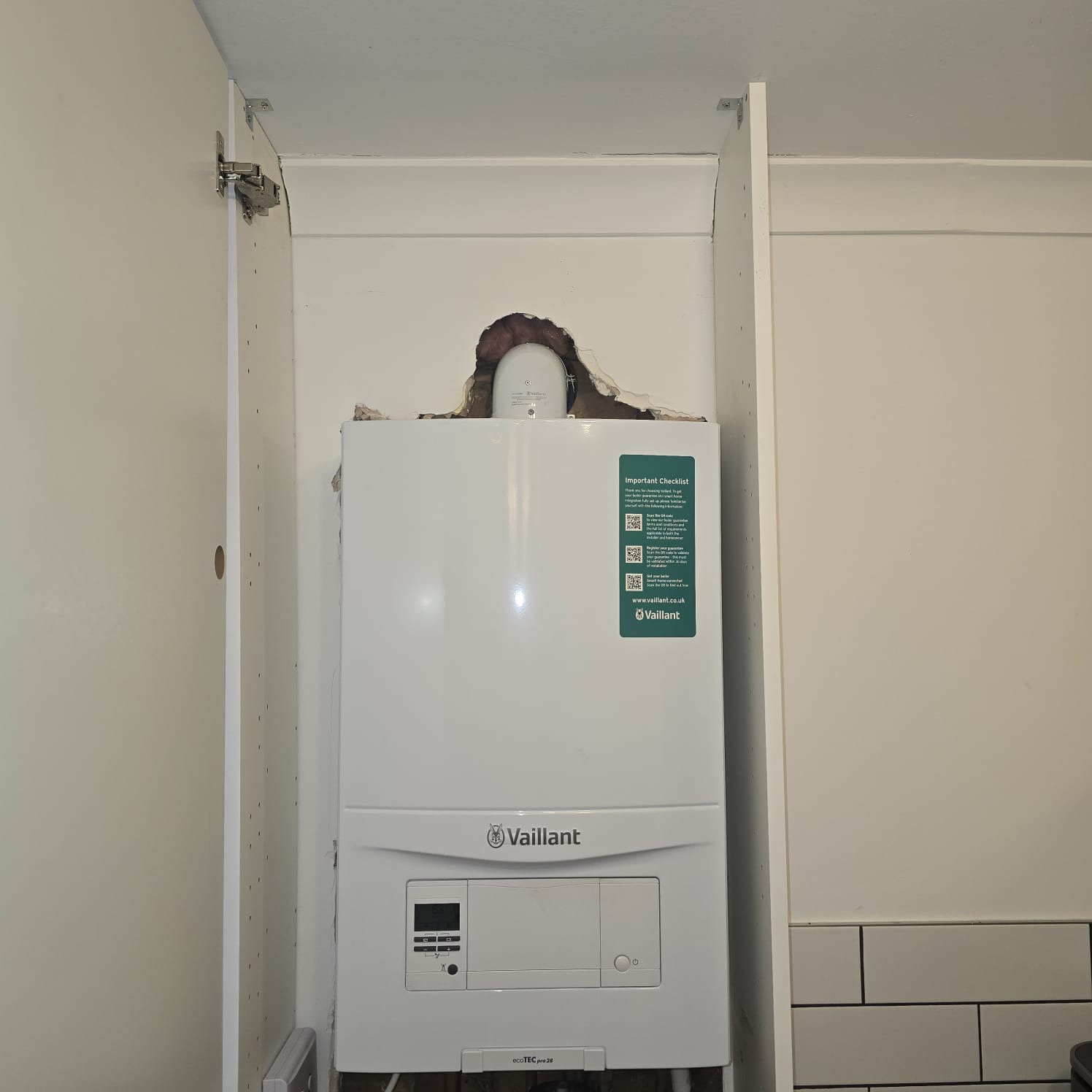 Vaillant boiler fitted inside a white kitchen cabinet with concealed pipework