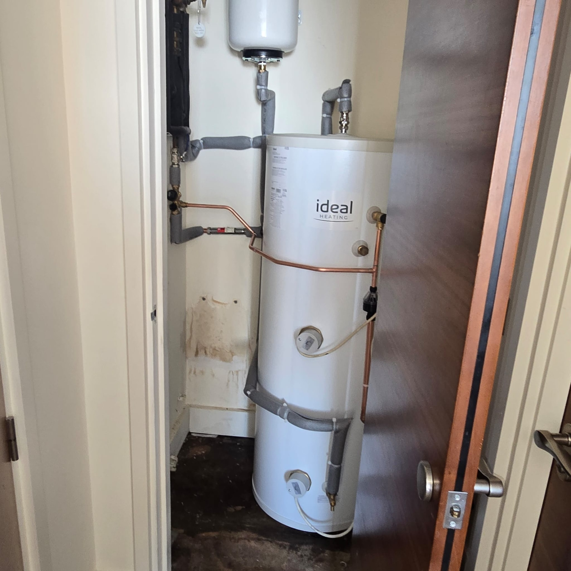 Ideal hot water cylinder installed in a utility cupboard with new pipework