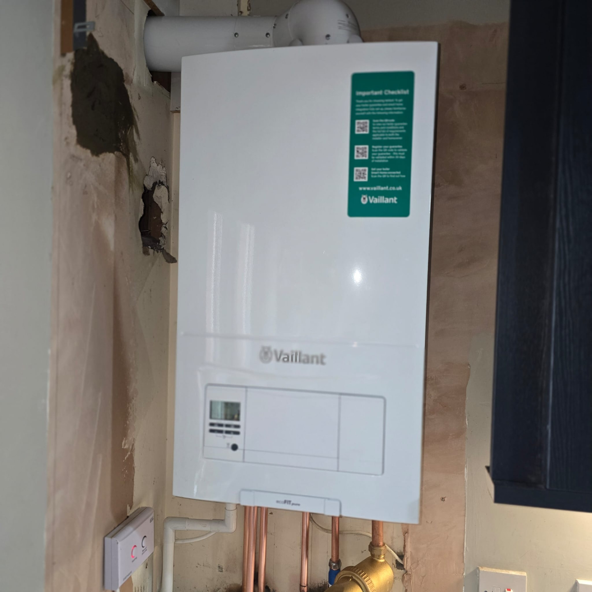 Kitchen boiler installation with wall made good next to dark cabinetry