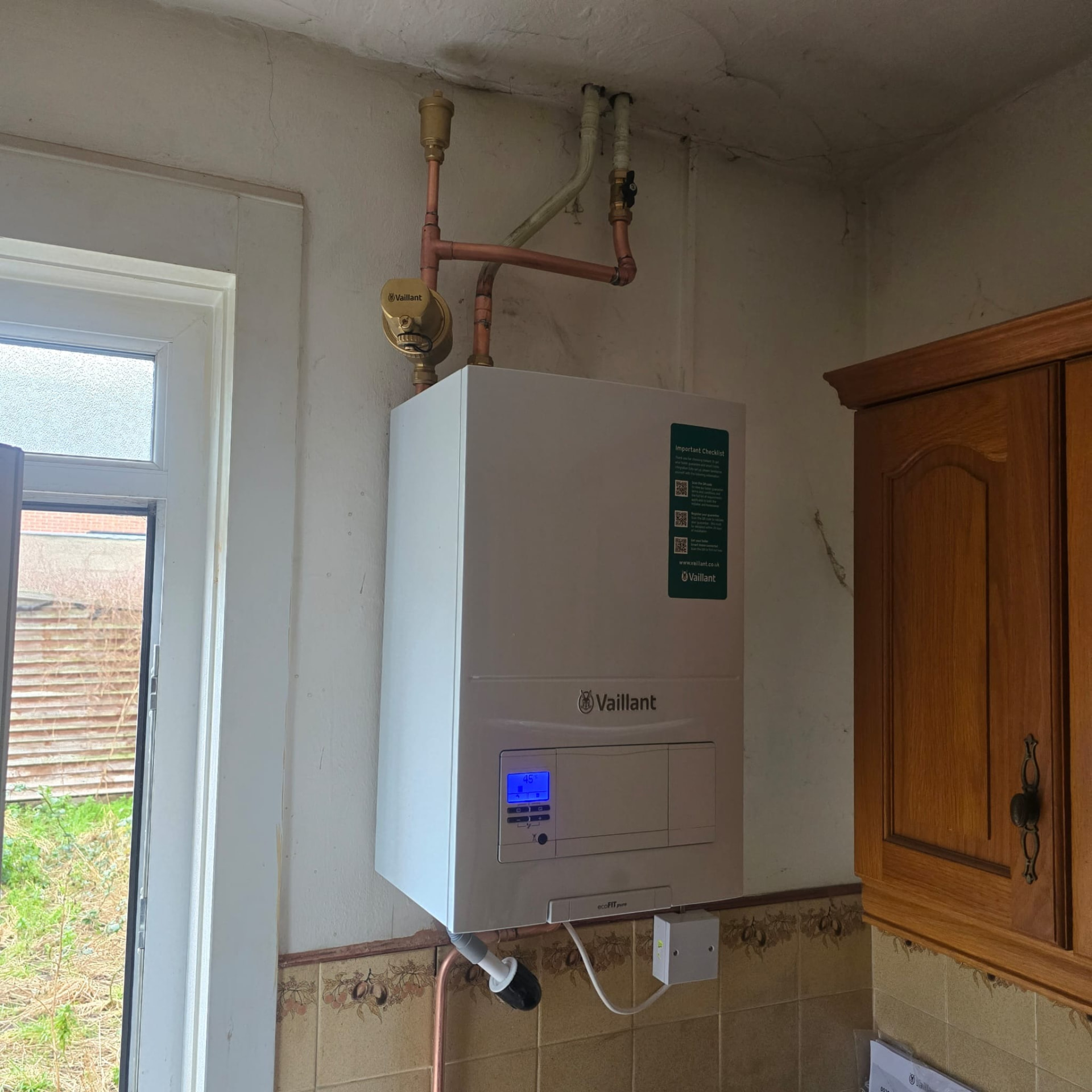 Wall-hung Vaillant combi boiler with copper pipes routed neatly through the ceiling