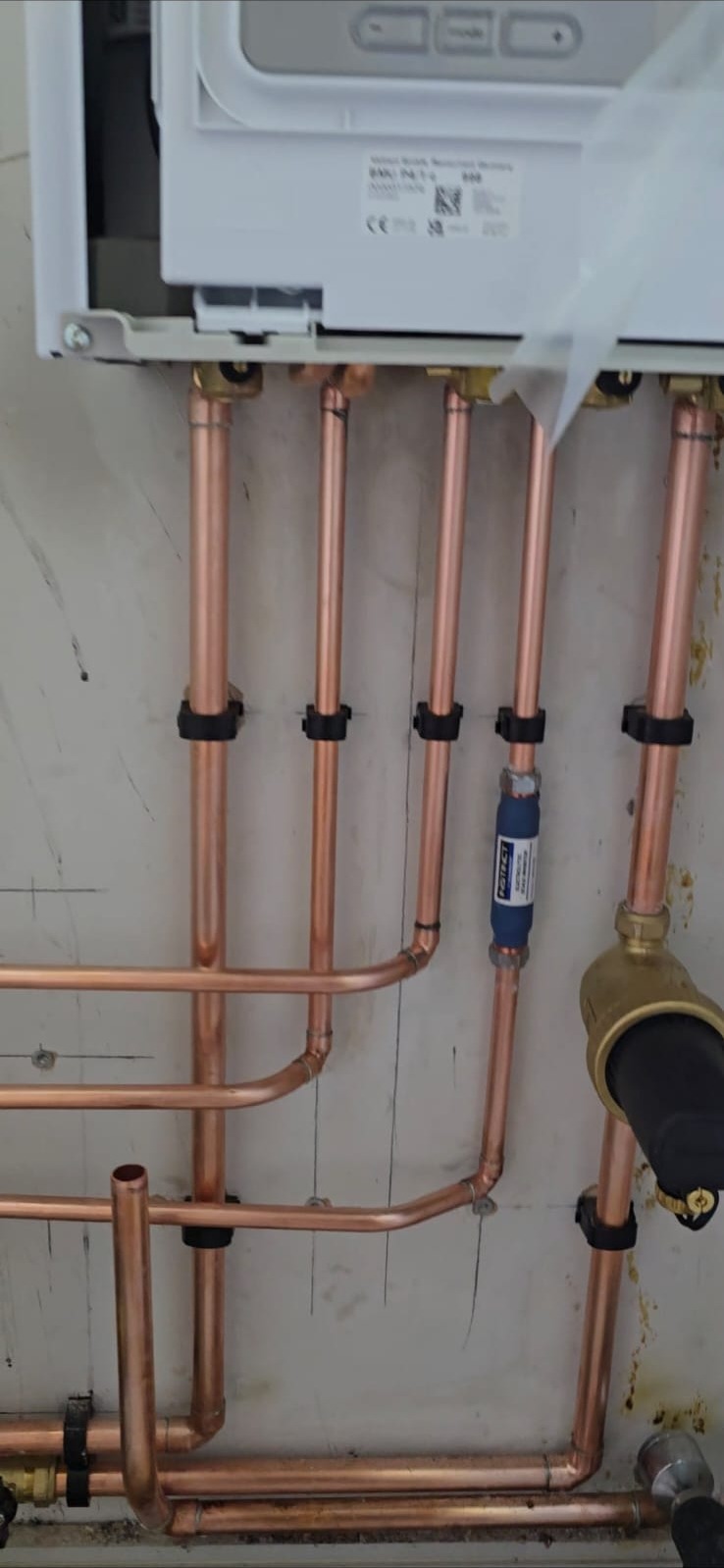 Neatly clipped vertical copper pipework beneath a newly installed gas boiler in Essex